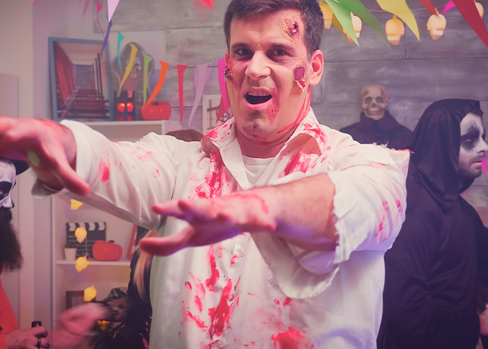 Hombre disfrazado de zombie con manchas de sangre en fiesta temática de Halloween, representando presentimientos desagradables.