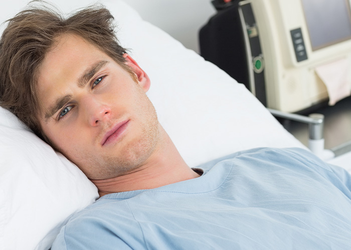Joven con presentimiento desagradable acostado en cama de hospital, mostrando expresión de preocupación y malestar.