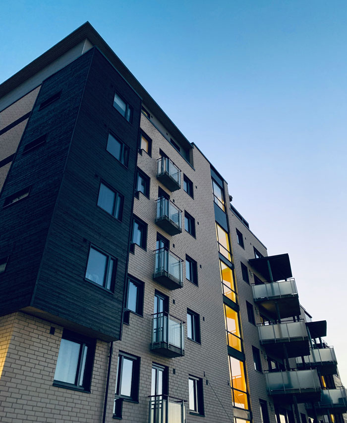 Edificio moderno con balcones de vidrio al atardecer representando tendencias hogareñas actuales de millennials.