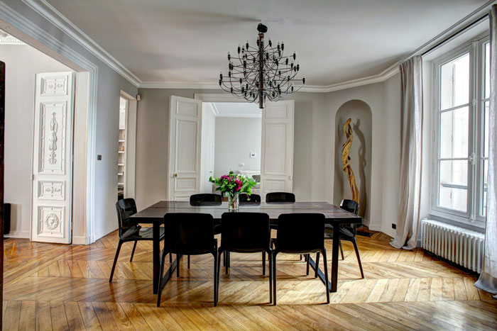 Comedor moderno con mesa negra, sillas minimalistas y detalles hogareños en espacio luminoso y elegante vintage.