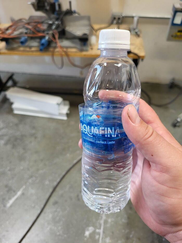 Botella de agua con etiqueta parcialmente arrancada en un taller, ejemplo de personas con un día peor en el trabajo.