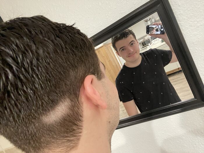 Hombre con corte de cabello defectuoso y parche en la cabeza mirando su reflejo, ejemplo de error en salón de belleza.
