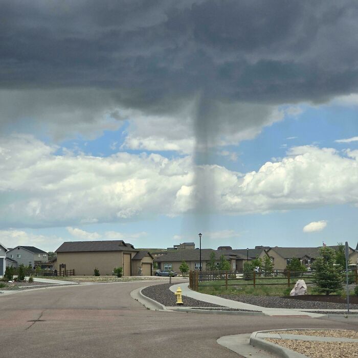 Momento divertido en la naturaleza con una columna de agua o tornado pequeño inesperado en zona residencial tranquila.