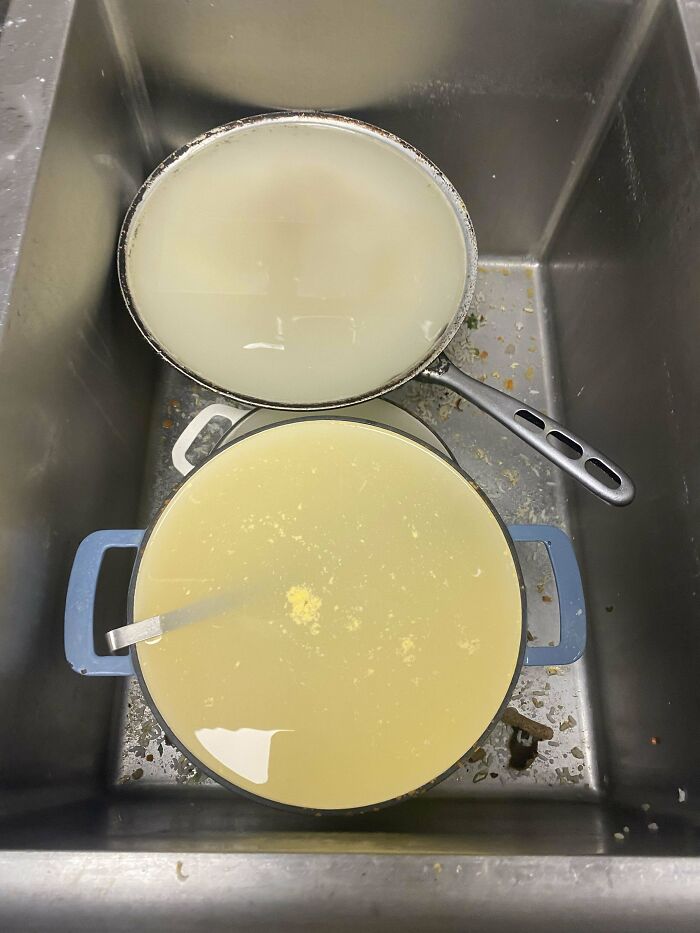 Dos ollas llenas de líquido en un fregadero sucio, mostrando una de las peores situaciones en el trabajo.