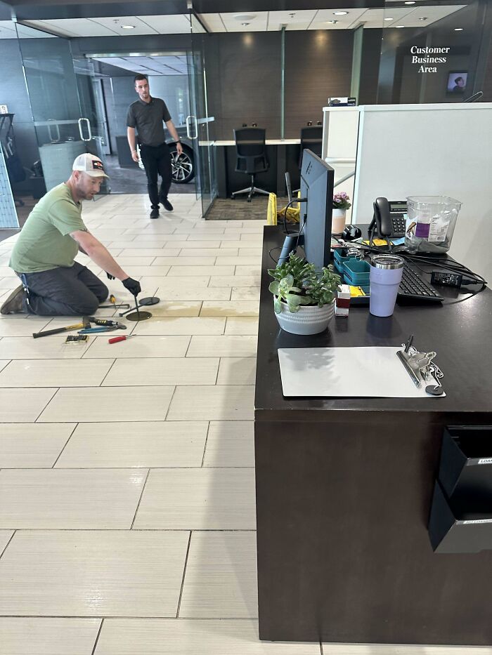 Hombre trabajando en reparación del suelo en oficina, mostrando un día difícil en el trabajo en oficina moderna.