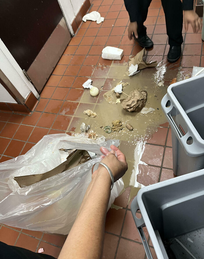 Persona recogiendo basura derramada en el suelo con desechos esparcidos, simbolizando un mal día en el trabajo.