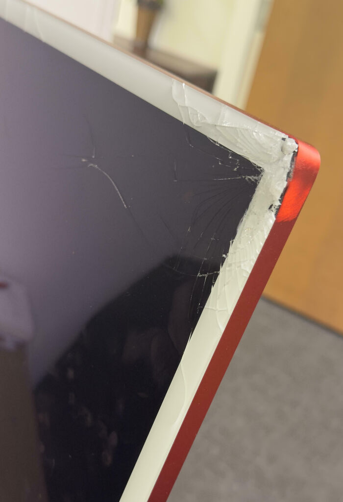 Pantalla de computadora con borde rojo y esquina rota, mostrando un mal día en el trabajo según personas cotidianas.