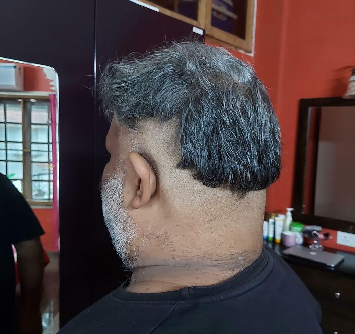 Hombre con corte de cabello mal hecho en salón de belleza, mostrando un resultado muy arrepentido y disgustado.