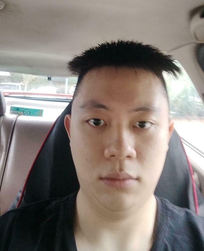 Hombre con corte de cabello desparejo y expresión triste tras salida de salón de belleza arrepentido y disgustado.