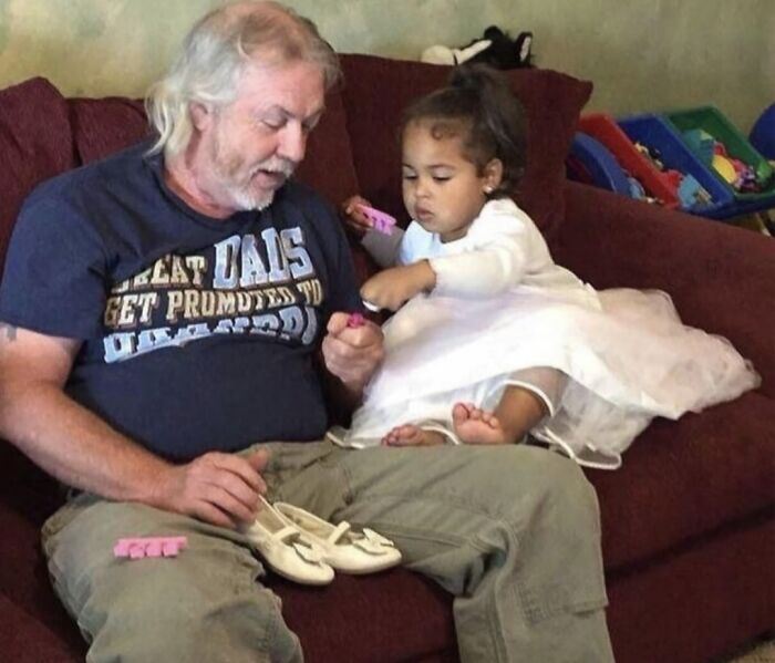 Hombre mayor y niña pequeña en sofá compartiendo un momento reconfortante para distraerse de horrores actuales.