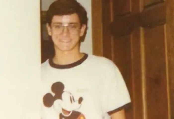 Joven con gafas y camiseta de Mickey Mouse, imagen vintage que refleja misterios interesantes y desconcierto en la gente.