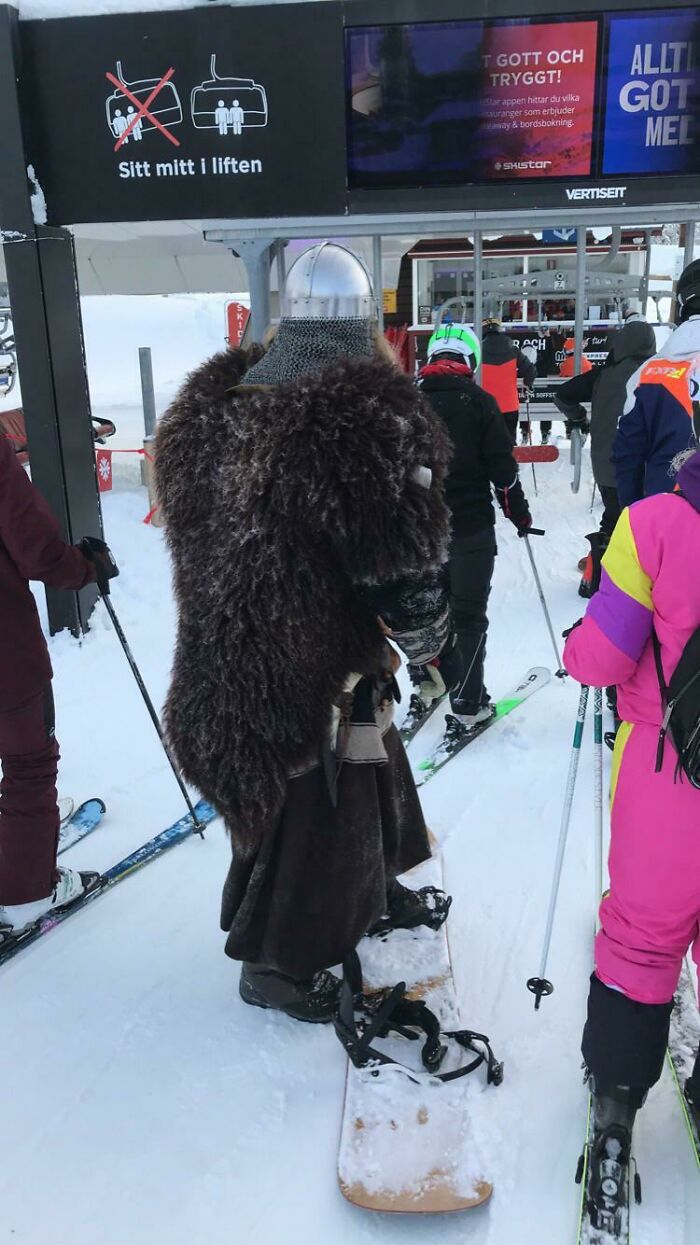 Persona a la que todo le da igual usando disfraz medieval en telesilla de estación de esquí con nieve alrededor.