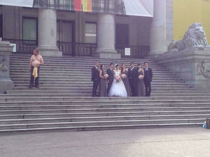 Hombre sin camisa ignorando a grupo de personas posando en escaleras, mostrando actitud de personas a las que todo les da igual.