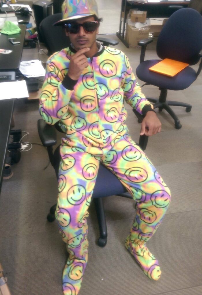 Hombre en oficina con ropa colorida de emojis sonrientes, mostrando actitud despreocupada y sin importar opiniones ajenas.