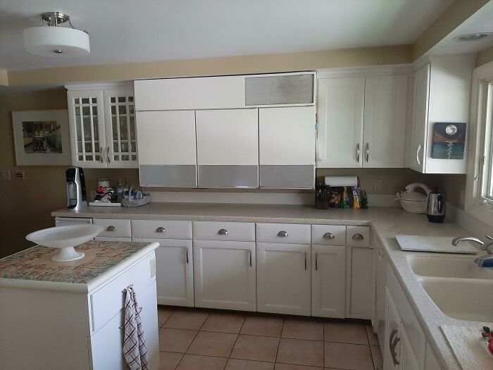 Cocina típica de la década de 1950 con muebles blancos y detalles que reflejan la vida cotidiana de esa época.