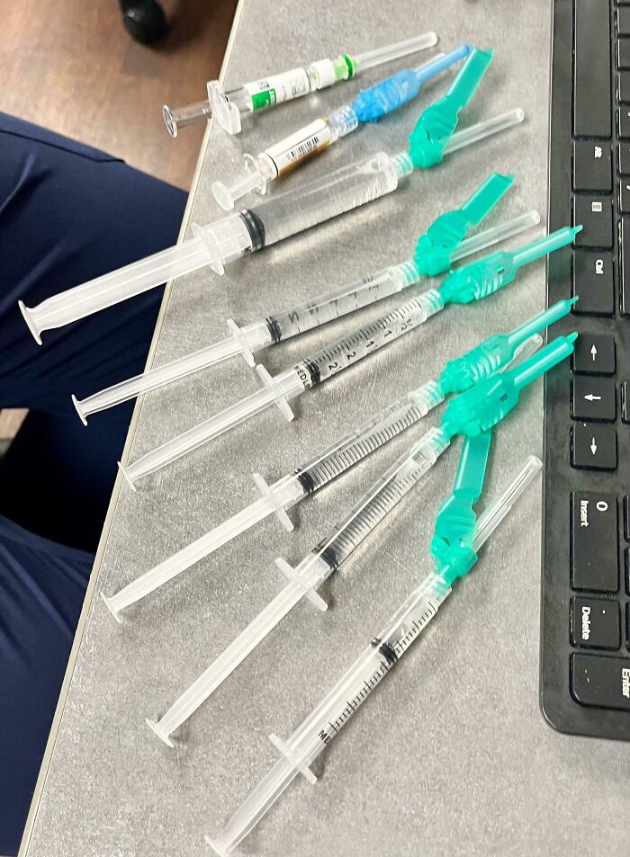 Varias jeringas y agujas médicas sobre una mesa junto a un teclado, ilustrando equipo médico en uso.