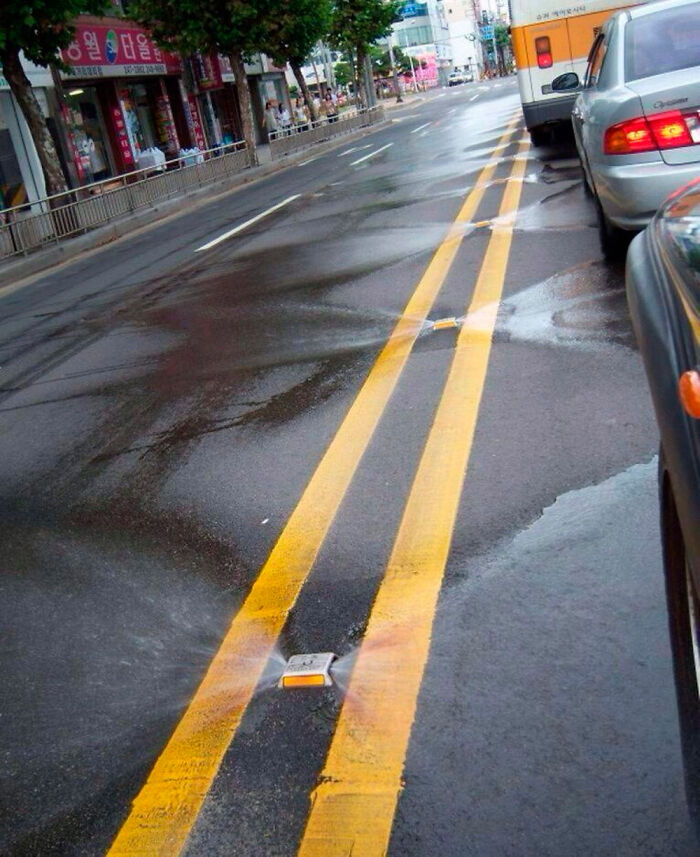Sistema de riego integrado en las líneas amarillas de la calle, un detalle ingenioso en la vida cotidiana urbana.