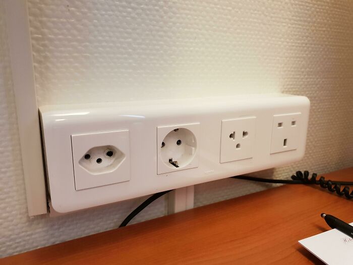 Variedad de enchufes eléctricos en pared mostrando detalles ingeniosos en la vida cotidiana de diversos países.