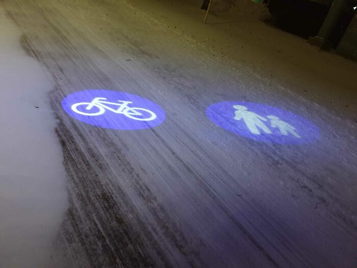 Proyección luminosa en suelo para separar carril bici y zona peatonal, detalle ingenioso en la vida cotidiana urbana.