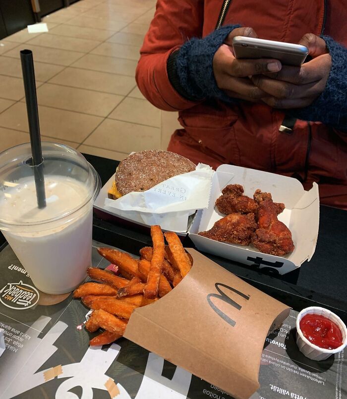 Persona usando teléfono móvil mientras disfruta detalles ingeniosos de comida rápida en varios países del mundo.