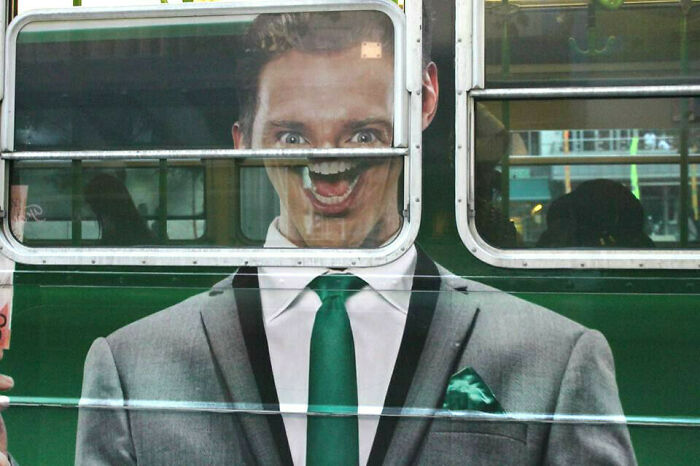 Hombre en anuncio publicitario en autobús con un fallo divertido que distorsiona su rostro en la ventana.