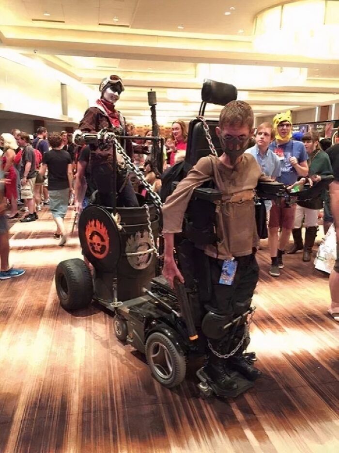 Persona disfrazada con silla de ruedas decorada y cadenas en evento de cosplay, una de las cosas interesantes que la gente encontró.
