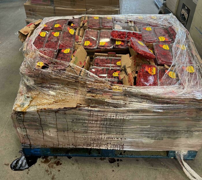 Palé de frambuesas dañado con líquido derramado, ejemplo claro de un fallo patético en el trabajo.