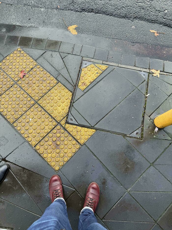 Fallo en pavimento con baldosas táctiles amarillas mal colocadas que crean un error visible en la acera.