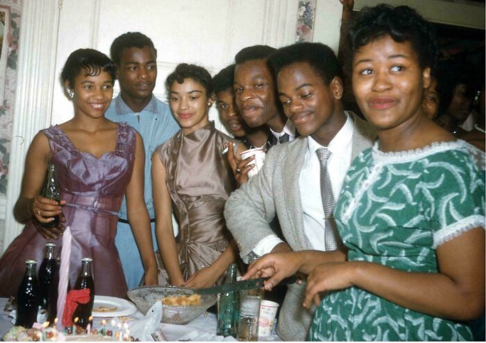 Grupo de jóvenes en fiesta histórica con comida y refrescos, foto antigua fascinante y cultural.