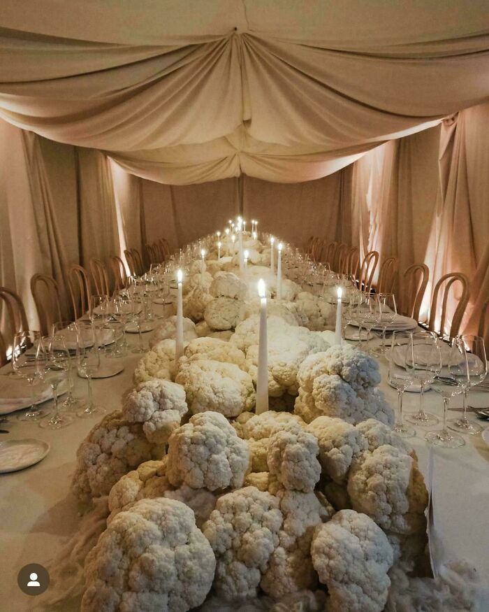 Mesa larga decorada con coliflores y velas encendidas en boda, mostrando estilo único de novios y invitados.