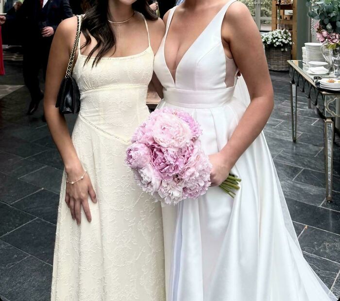 Novia y mujer invitada en boda, vestidos blancos elegantes, ramo de flores rosas, momento destacado de boda y asistentes.