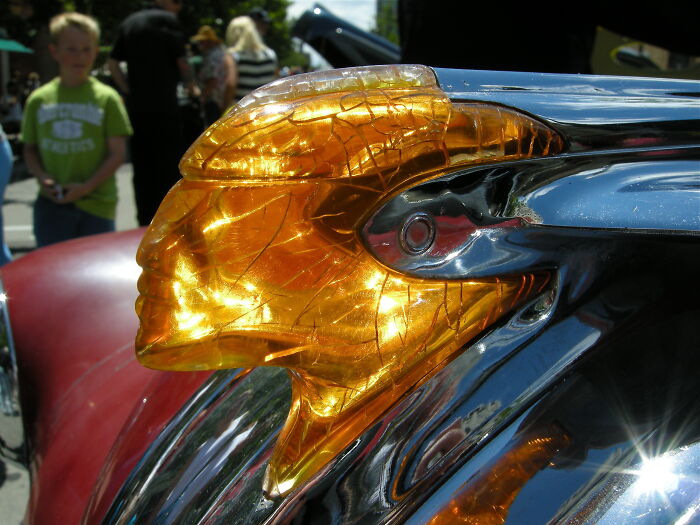 Detalle de adorno automotriz dorado de la década de 1950 mostrando vida cotidiana en imágenes impresionantes.