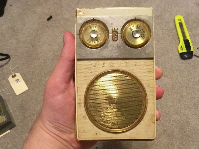 Radio portátil Zenith vintage sostenida a mano, mostrando tecnología y objetos cotidianos de la década de 1950.