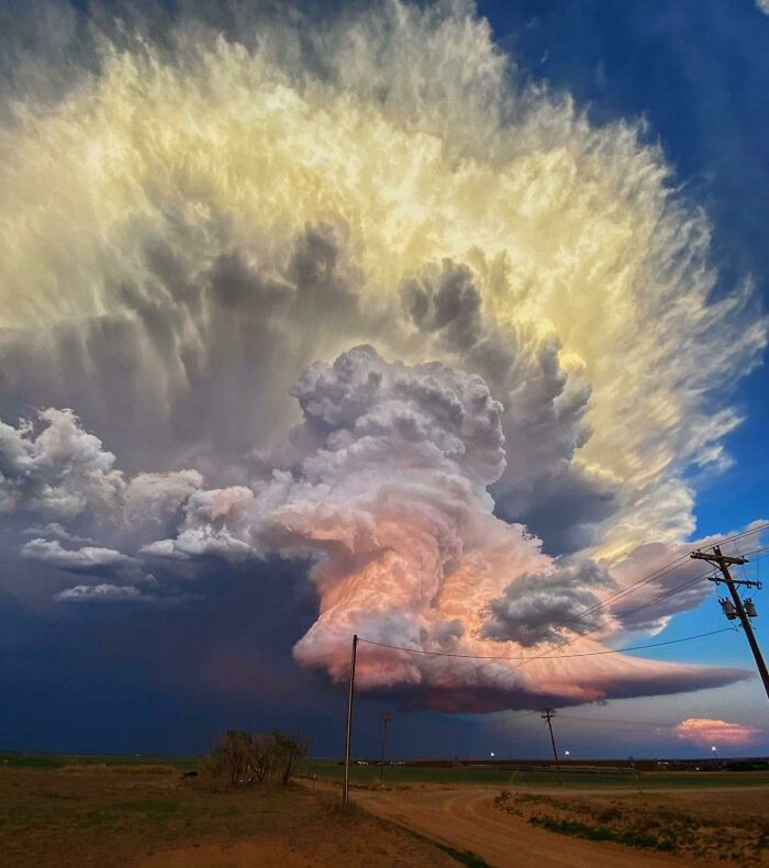 Nube gigante y amenazante con luces de atardecer en un paisaje rural, creación de la madre naturaleza impresionante y aterradora.