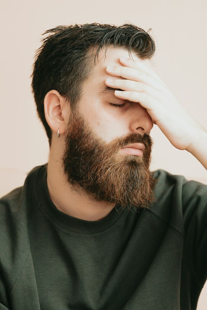 Hombre con barba y sudadera verde mostrando frustración al recordar las peores cosas que escuchó accidentalmente.