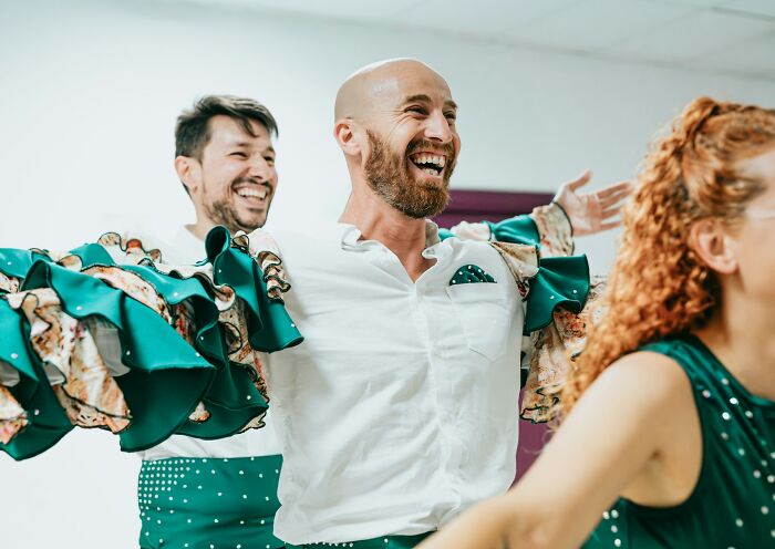 Hombres felices en clase de baile con trajes verdes, reflejando alegría y camaradería en momentos inolvidables para detectives privados.