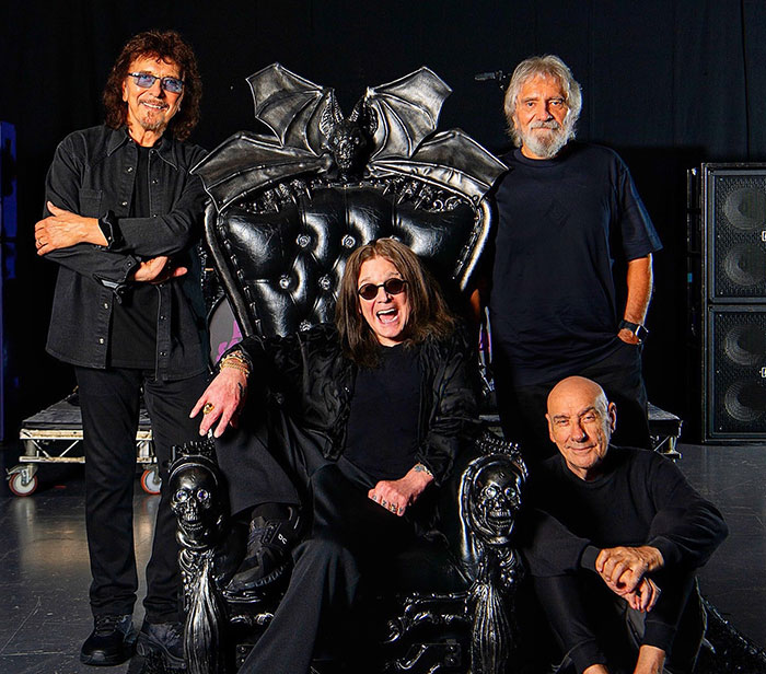 Miembros de Black Sabbath posan alrededor de un trono gótico, compartiendo declaraciones emotivas sobre el fallecimiento de Ozzy Osbourne.