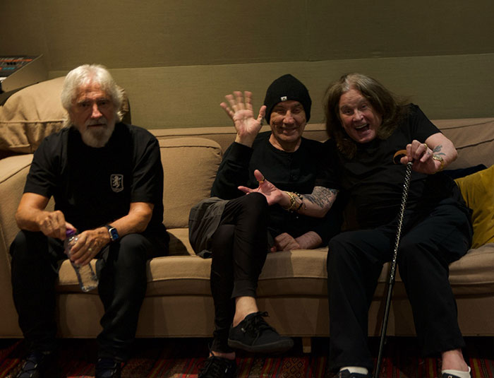 Miembros de Black Sabbath sentados en un sofá, compartiendo declaraciones emotivas tras el fallecimiento de Ozzy Osbourne.