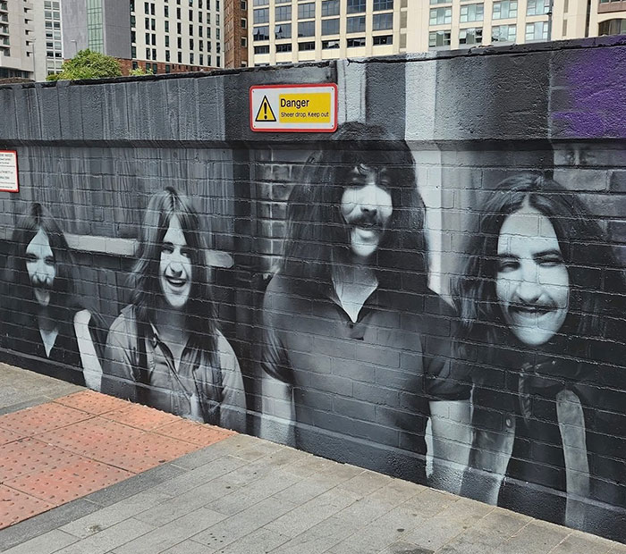 Mural urbano de Black Sabbath en pared de ladrillo, homenaje y declaraciones emotivas por fallecimiento de Ozzy Osbourne.