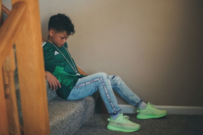 Niño sentado en escaleras con ropa deportiva, reflejando emociones tras escuchar cosas peores accidentalmente.