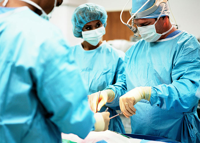 Equipo de médicos en cirugía usando ropa y equipo quirúrgico, atendiendo un caso urgente para diagnóstico temprano.
