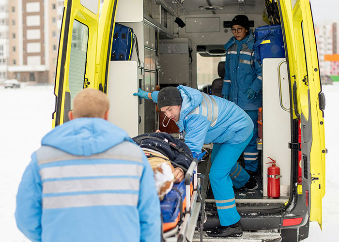 Paramédicos atendiendo un caso médico urgente en ambulancia durante condiciones de clima frío y nieve.
