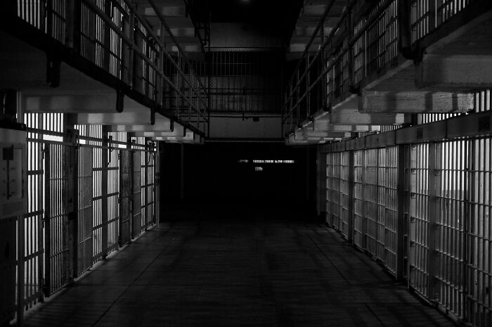 Pasillo oscuro de prisión con celdas a ambos lados, simbolizando el dilema moral y secretos que las empresas ocultan.
