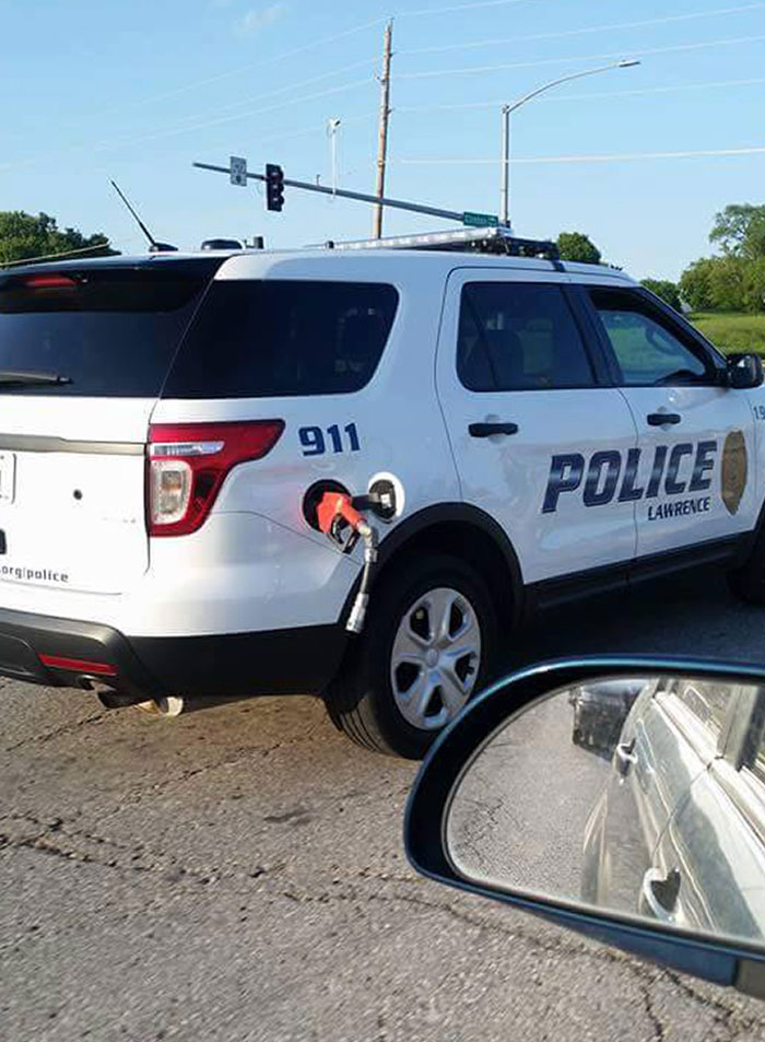 Policía con auto que olvidó retirar la manguera de la gasolinera, ejemplo de personas que olvidaron algo importante.