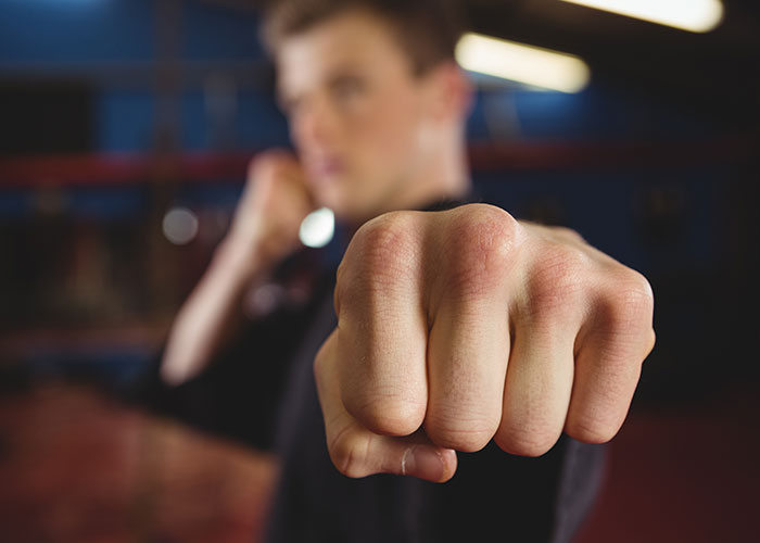 Persona con instinto de supervivencia fuerte mostrando puño cerrado en primer plano en ambiente de entrenamiento.