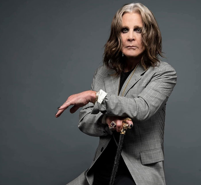 Músico de rock en traje gris representa la respuesta emocional de los miembros de Black Sabbath tras la muerte de Ozzy Osbourne.
