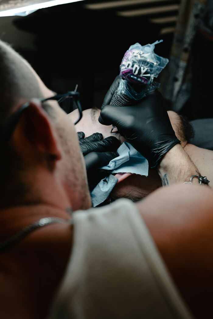 Persona tatuándose en primer plano, representando 20 personas que ignoraron su intuición y lo lamentaron.