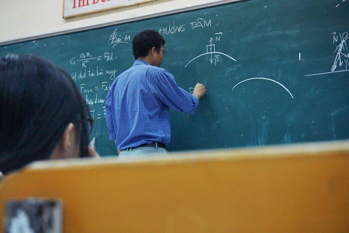 Profesor explicando conceptos en clase, destacado entre 20 personas que ignoraron su intuición y lo lamentaron.