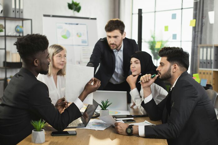Grupo diverso de profesionales discutiendo documentos y datos, ilustrando personas que ignoraron la intuición en reuniones.
