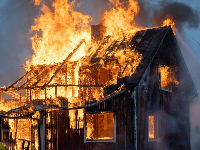 Casa en llamas consumida por fuego intenso, ilustrando situaciones desquiciadas y horribles en familias.